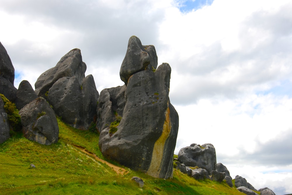 gray rock formation on green grass field under white cloudy sky during daytime
