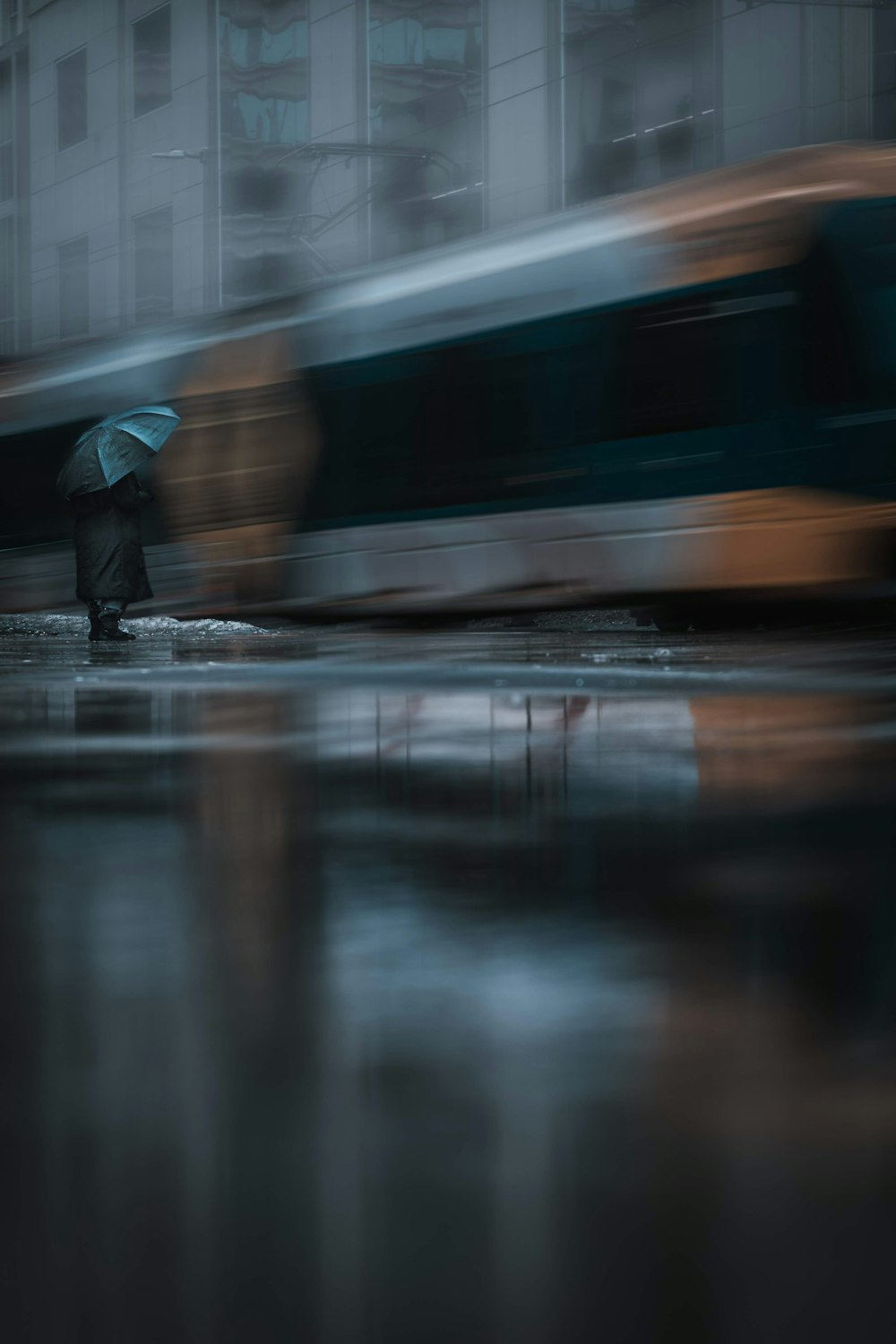 person in black jacket walking on wet road