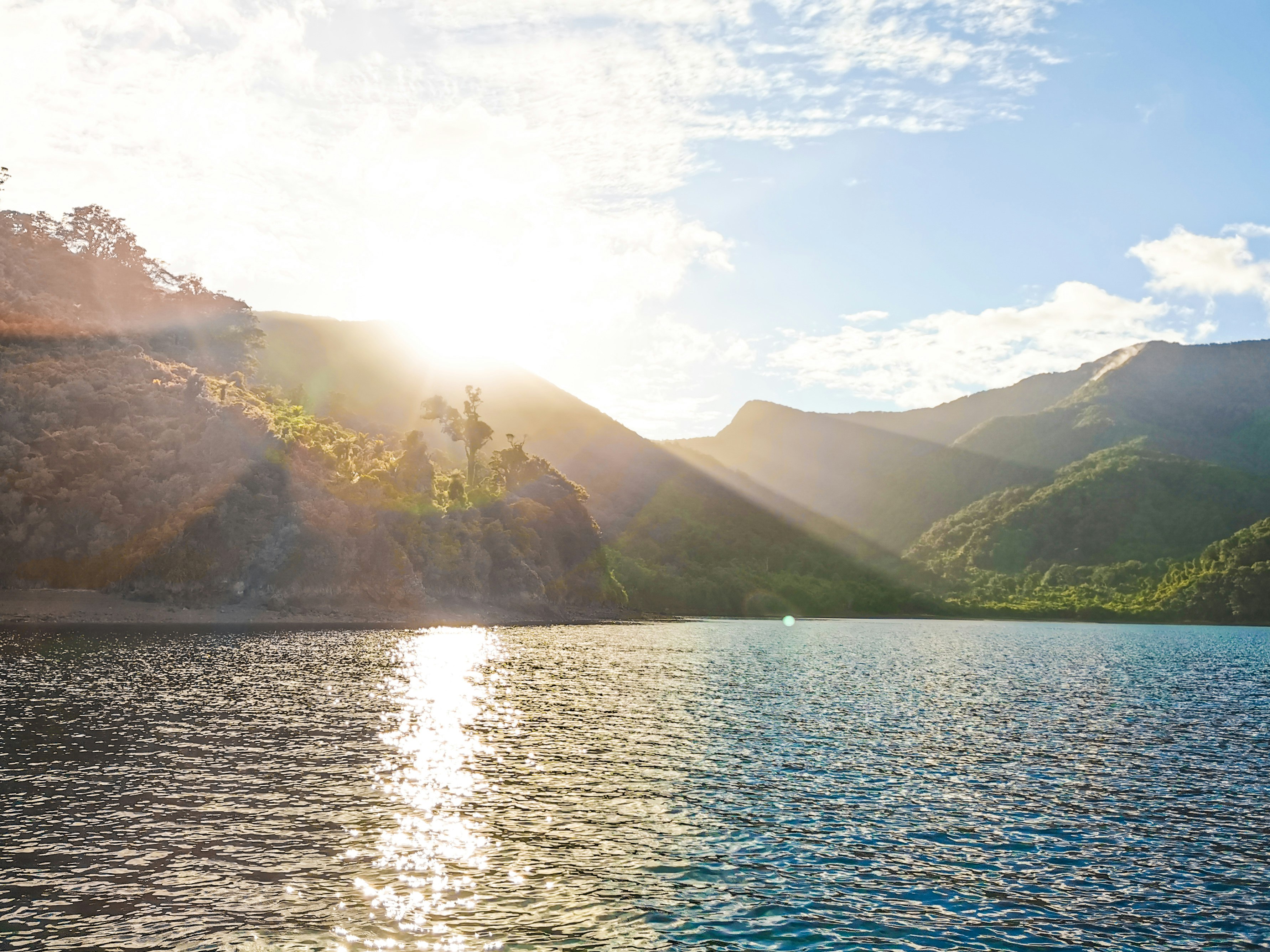 green mountains beside body of water during daytime