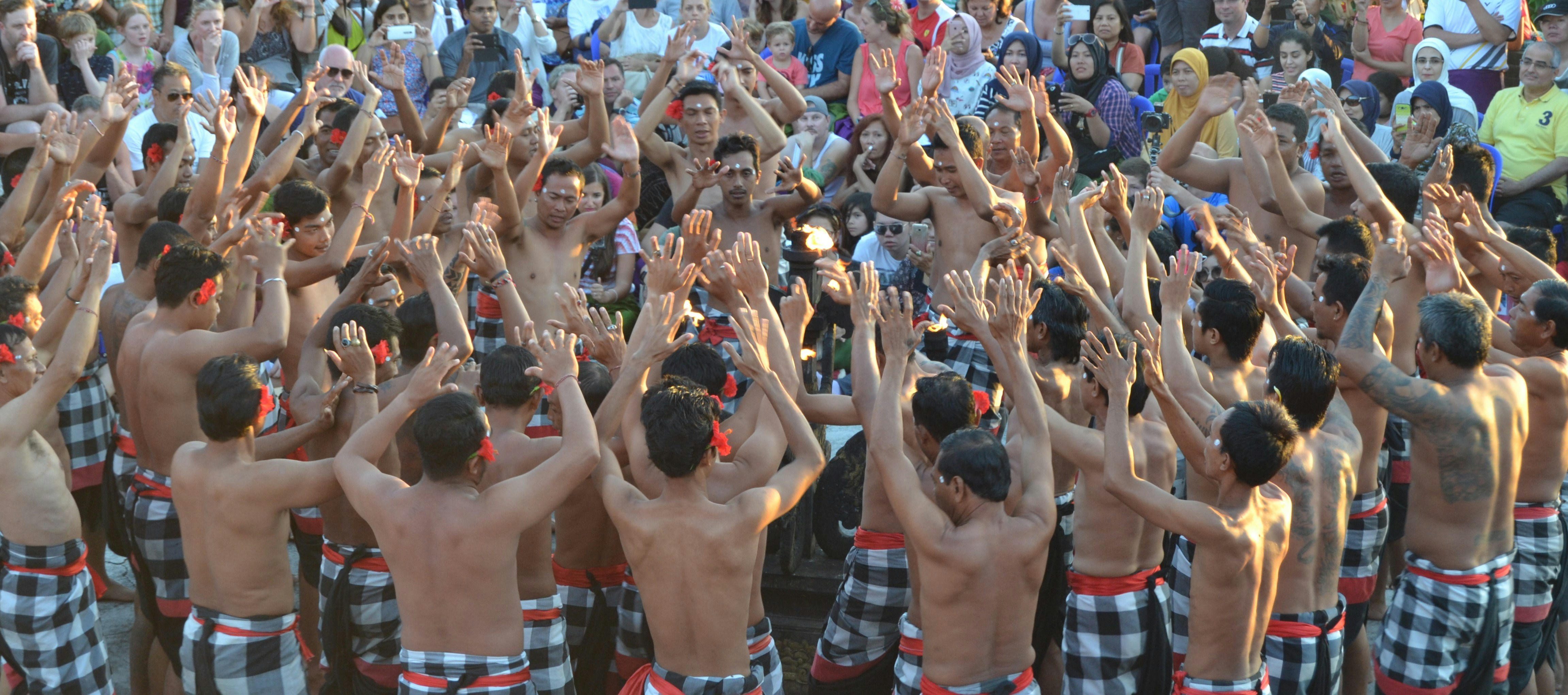 group of people raising their hands, Kecak Dance which is performed in the area of Uluwatu Temple, Bali. This dance actually presents the Ramayana story with several main characters, namely Rama, Shinta, Hanoman and Rahwana