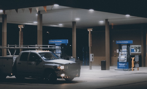 A fuel distribution truck parked at a gas station ready for service.