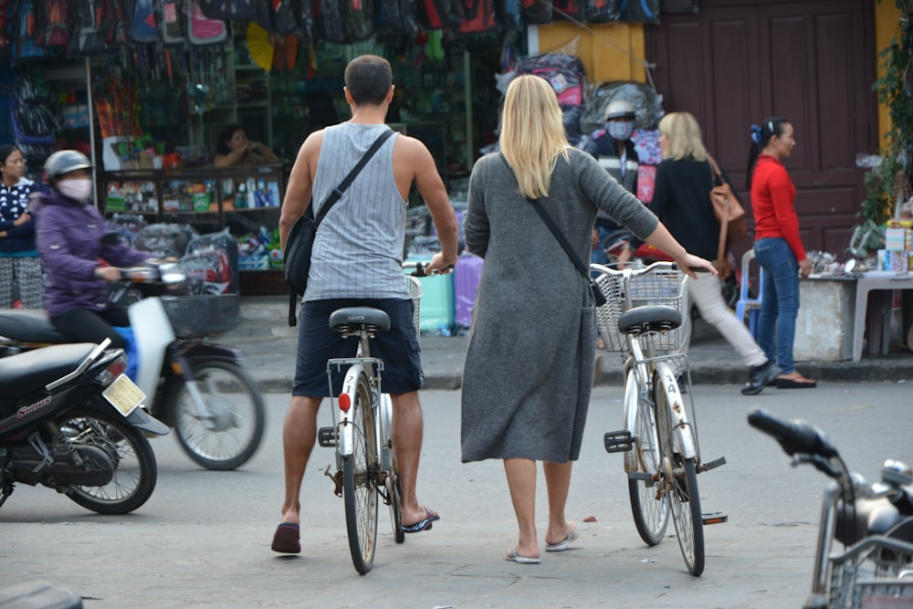 mulher no vestido cinzento sem mangas que anda na bicicleta durante o dia