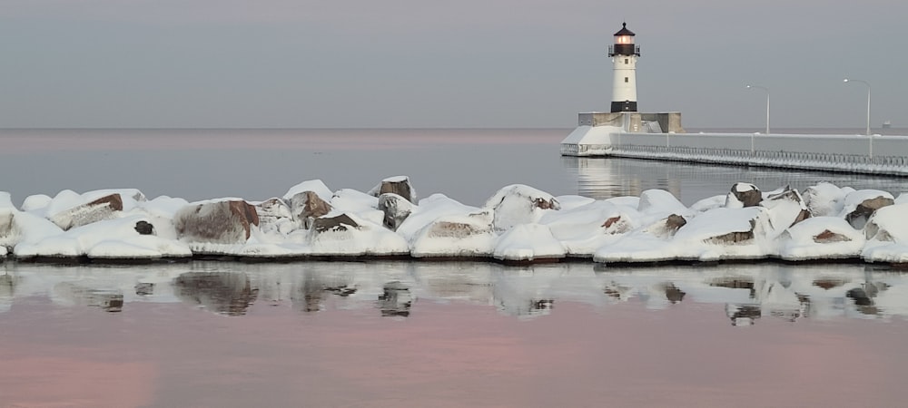 white and black lighthouse covered by snow