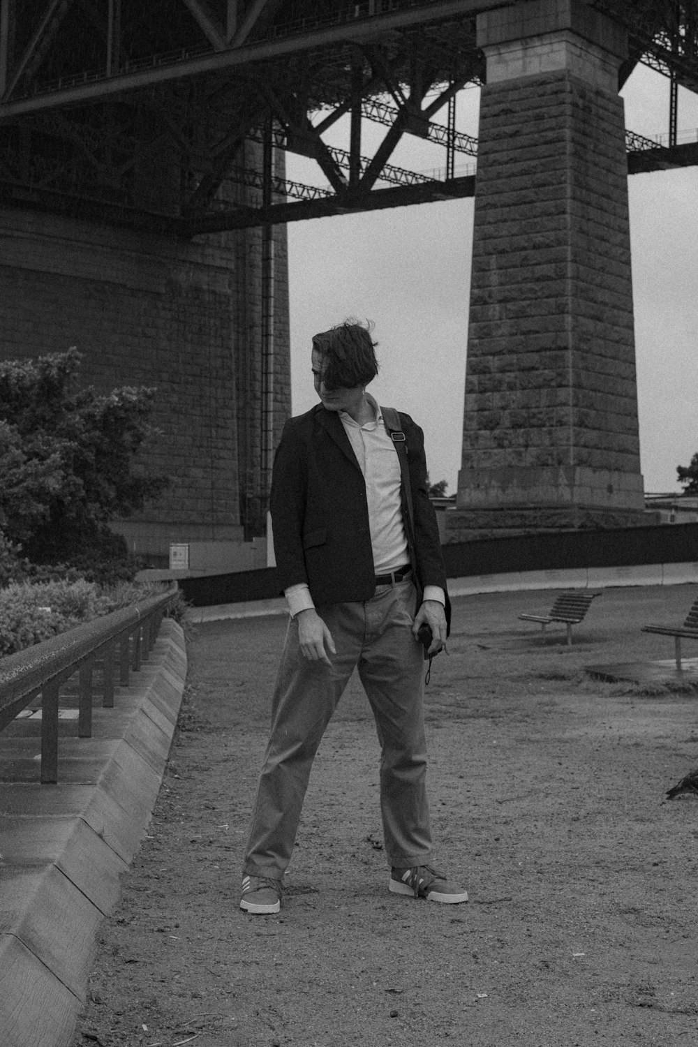 Mann in schwarzer Jacke und grauer Hose steht tagsüber in der Nähe eines Betongebäudes
