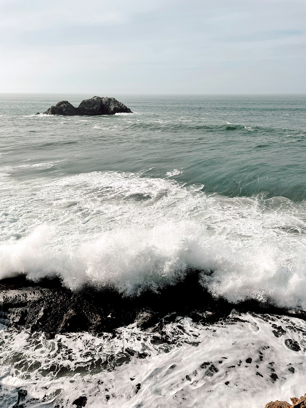 ocean waves crashing on black rock formation during daytime