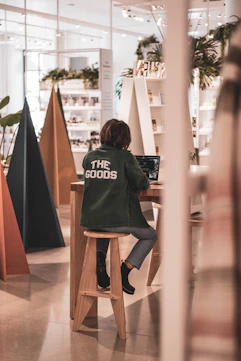 woman in green crew neck t-shirt and gray denim jeans sitting on brown wooden chair