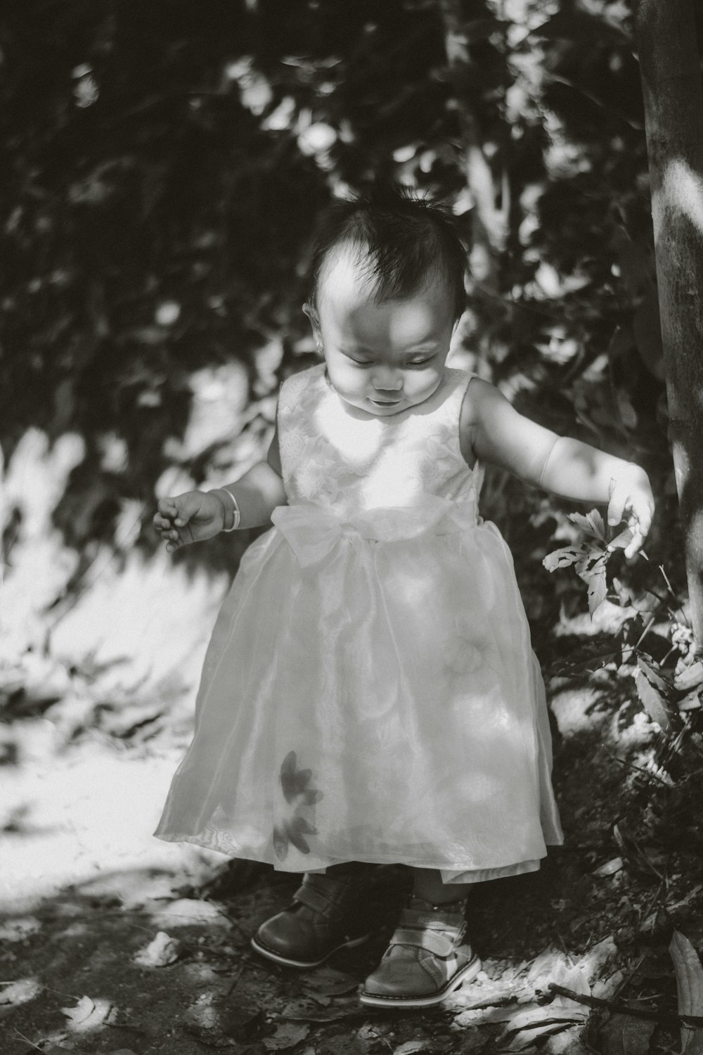 girl in white dress standing near tree