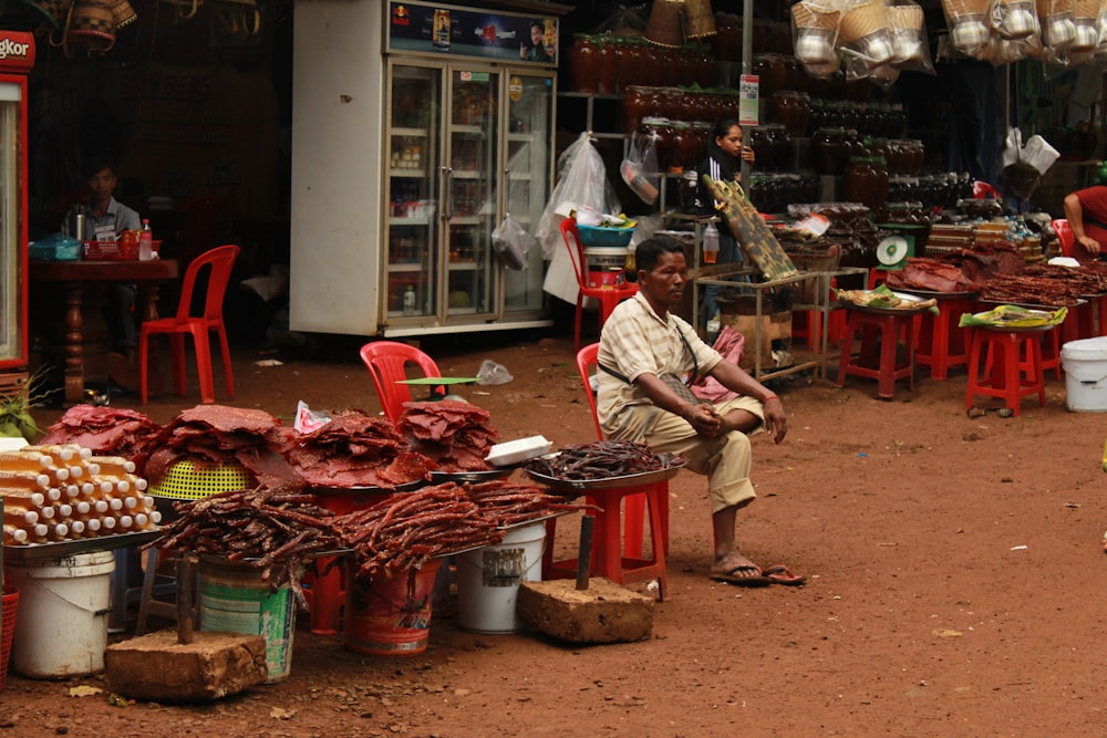 man in white and red plaid dress shirt and brown pants sitting on brown wooden seat