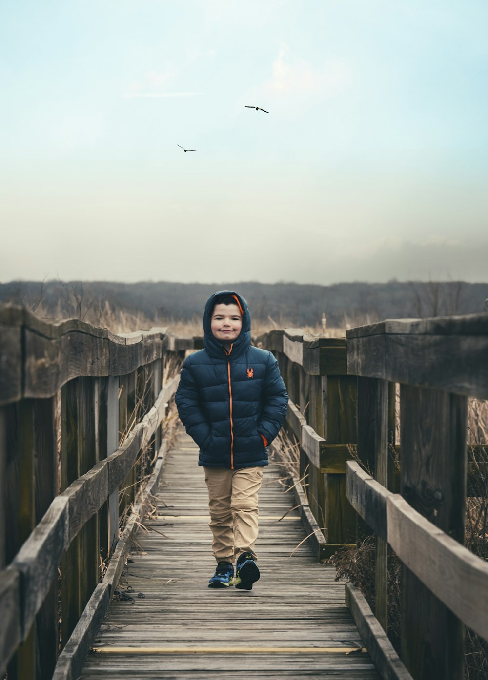 Femme en veste bleue et pantalon noir debout sur un pont en bois