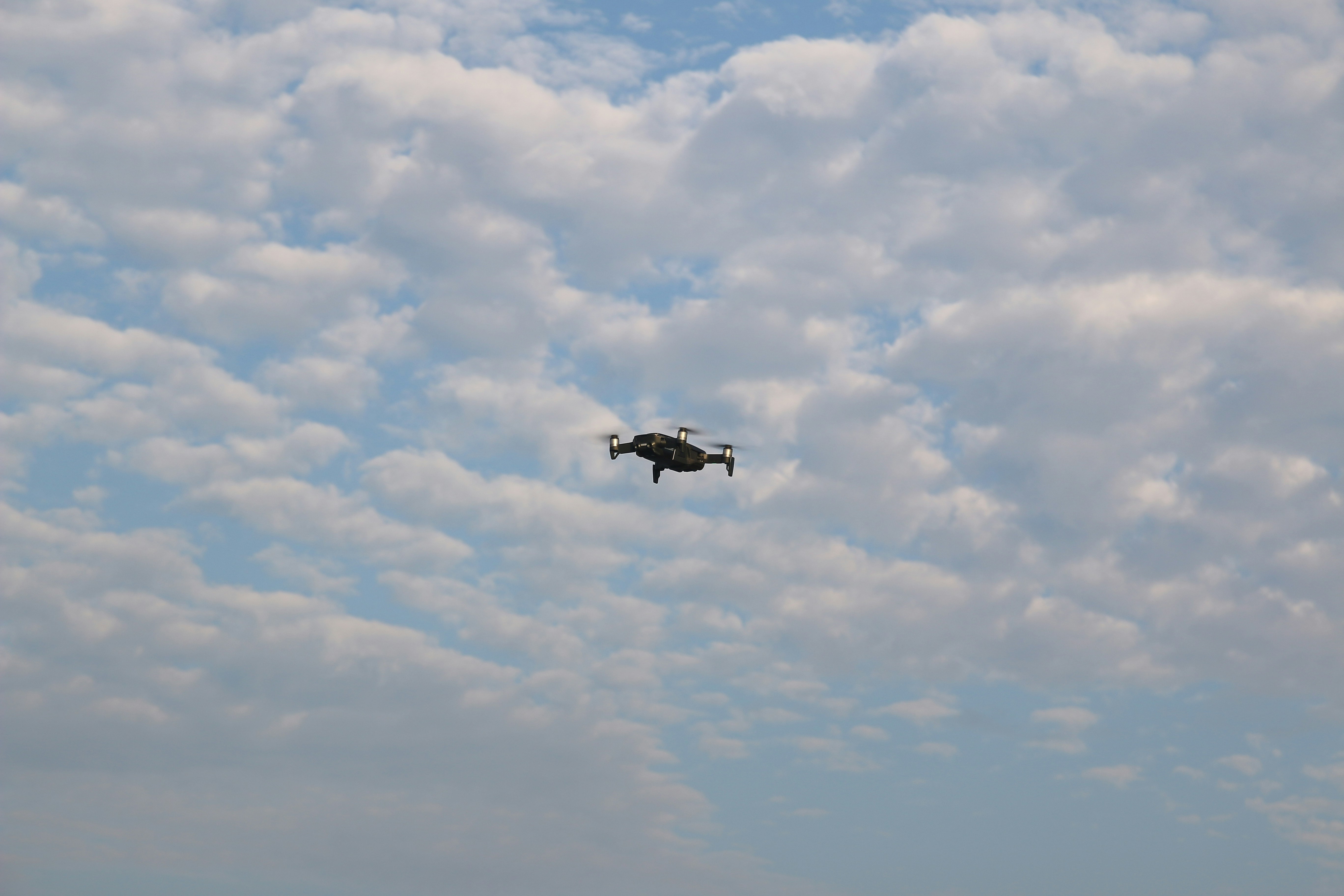 white and black airplane flying under white clouds during daytime