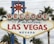 A large, iconic sign reads 'Welcome to Fabulous Las Vegas Nevada' with vintage-style lettering. The sign is topped with a red star and flanked by palm trees against a cloudy sky.