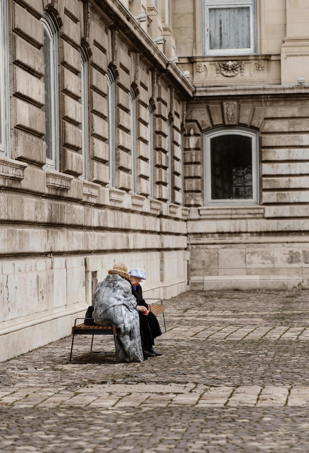 person in gray jacket sitting on brown wooden bench