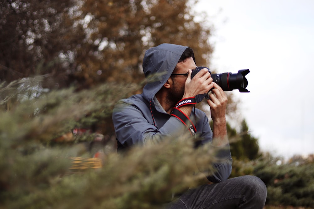 man in black jacket holding black dslr camera