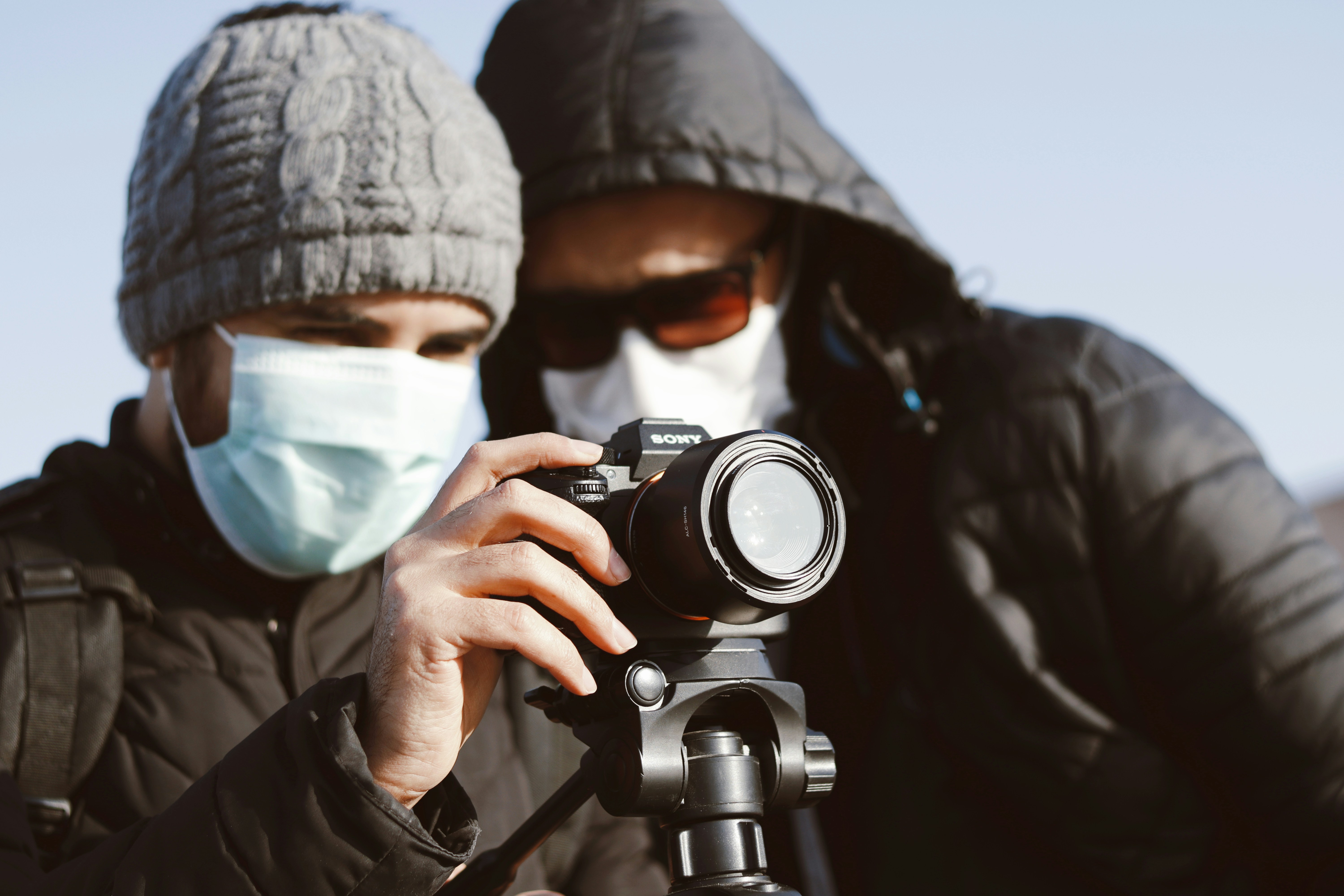 man in black knit cap holding black dslr camera