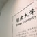 A wall with a framed plaque displays the text 'Hunan University' in both Chinese and English. The white background contrasts with the black text, which includes a description in Chinese characters.