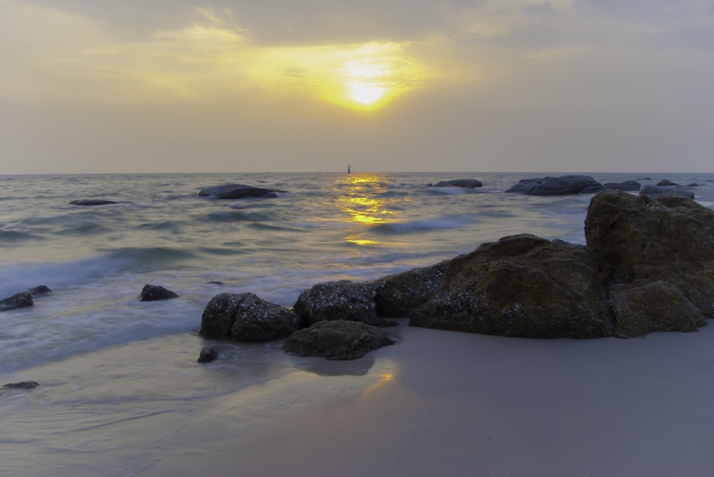 rocky shore with sea waves crashing on shore during sunset