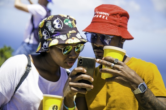 man in white crew neck t-shirt wearing red and blue cap holding yellow cup