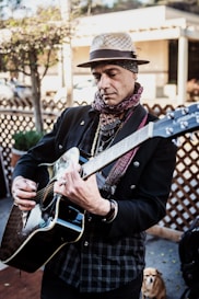 man in black coat playing white and black electric guitar