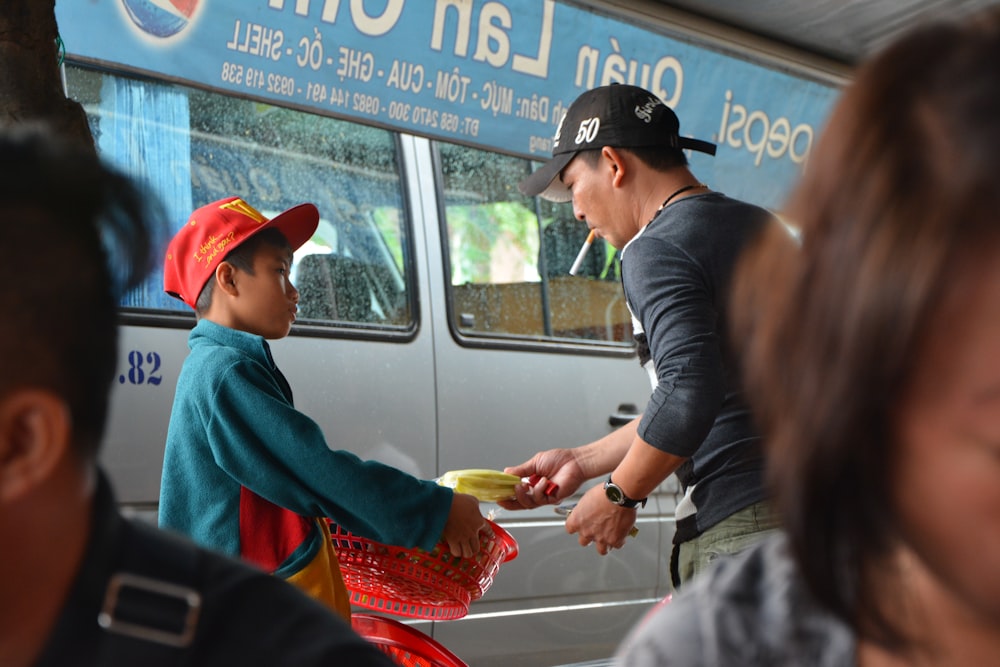 man in blue shirt and black cap holding red plastic bag