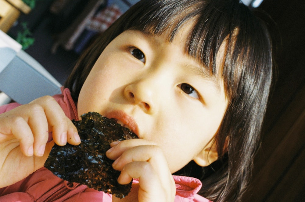 girl in white and red shirt holding chocolate cake