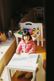 girl in pink and white plaid dress shirt sitting on brown wooden chair
