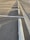 An empty parking lot with lined parking spaces, concrete wheel stops, and shadows cast by the setting sun along the asphalt surface.