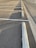 An empty parking lot with lined parking spaces, concrete wheel stops, and shadows cast by the setting sun along the asphalt surface.