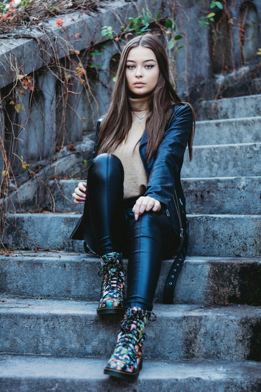 woman in black leather jacket and black pants sitting on concrete stairs