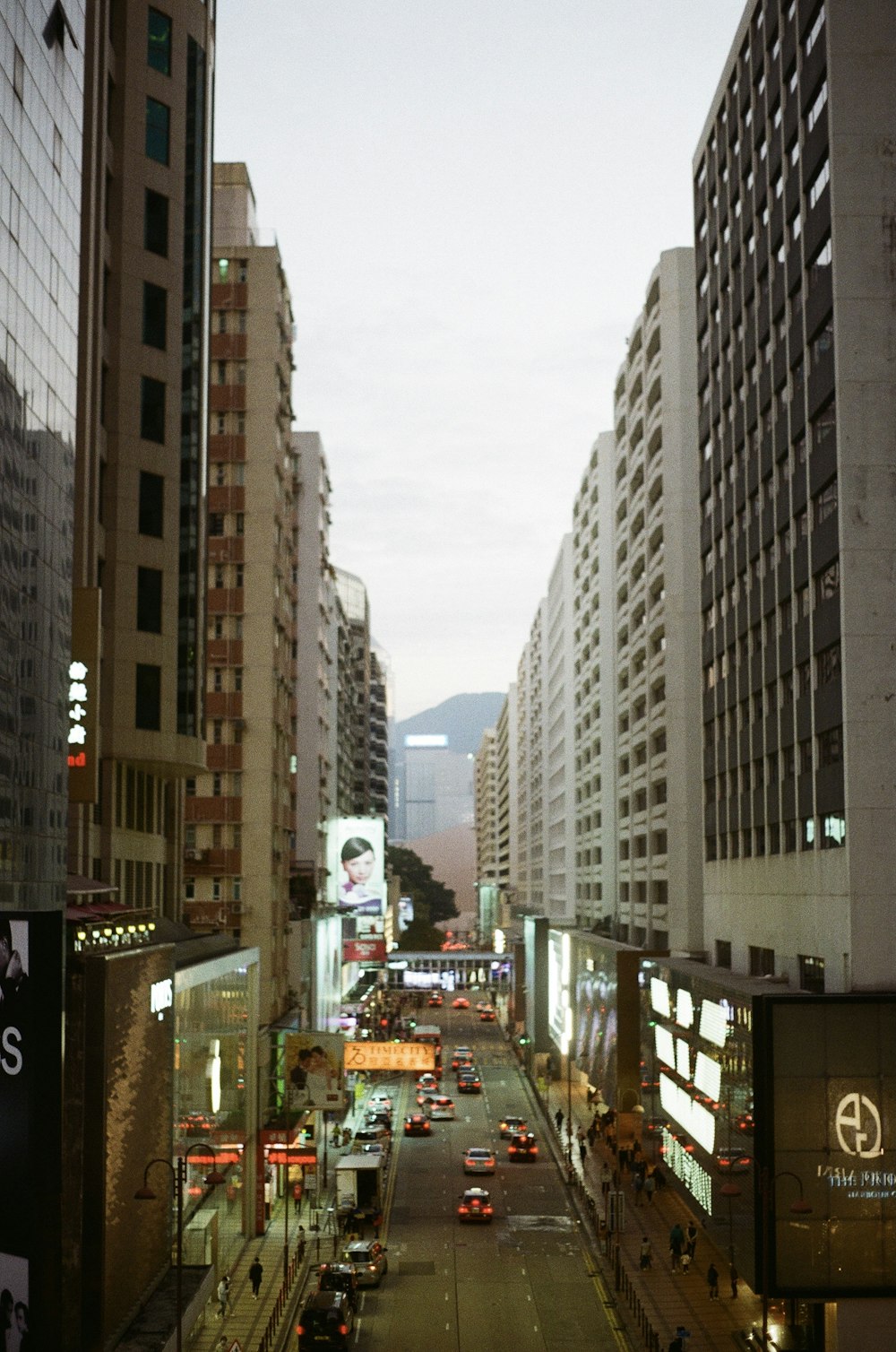 cars on road between high rise buildings during daytime