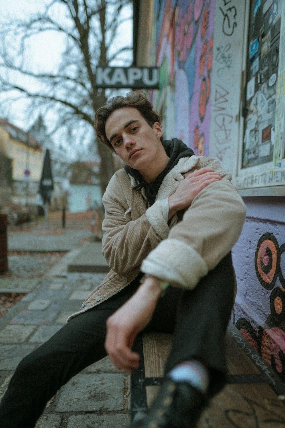 man in brown jacket sitting on concrete bench during daytime