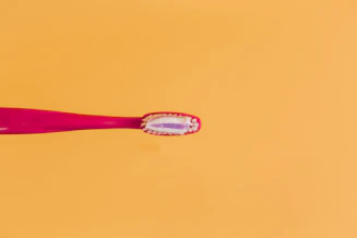 pink and yellow toothbrush on orange background