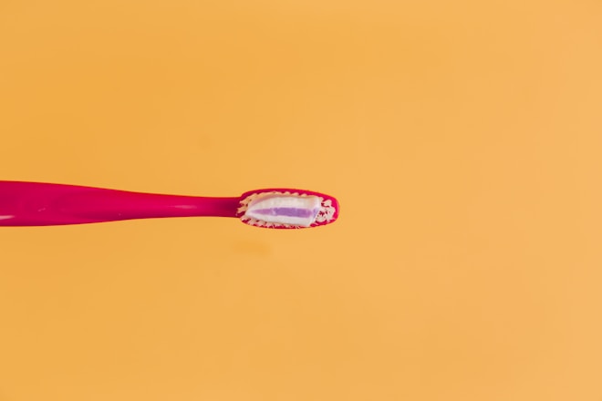 pink and yellow toothbrush on orange background