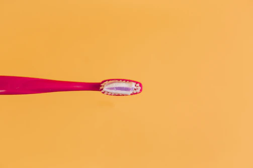 pink and yellow toothbrush on orange background