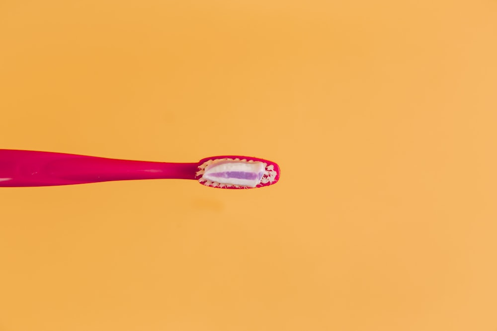 rosa und gelbe Zahnbürste auf orangem Hintergrund