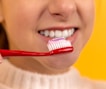 girl with red and white toothbrush in mouth