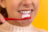 girl with red and white toothbrush in mouth