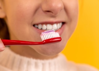 girl with red and white toothbrush in mouth