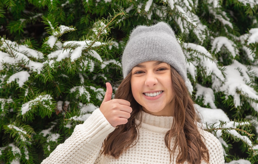 ragazza sorridente in maglione bianco e berretto in maglia grigia