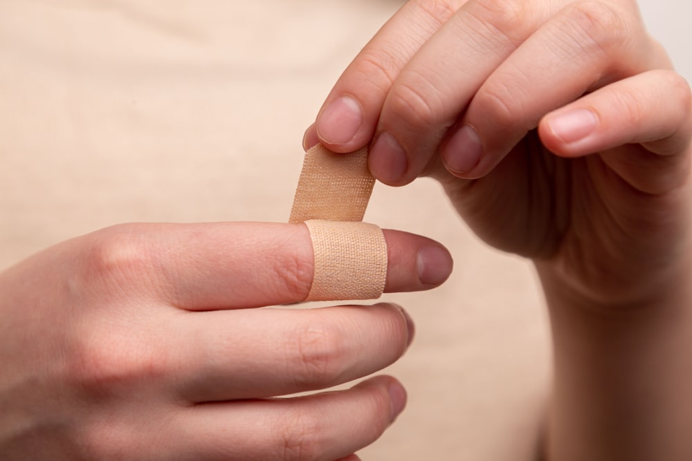 pessoa com band-aid no dedo médio