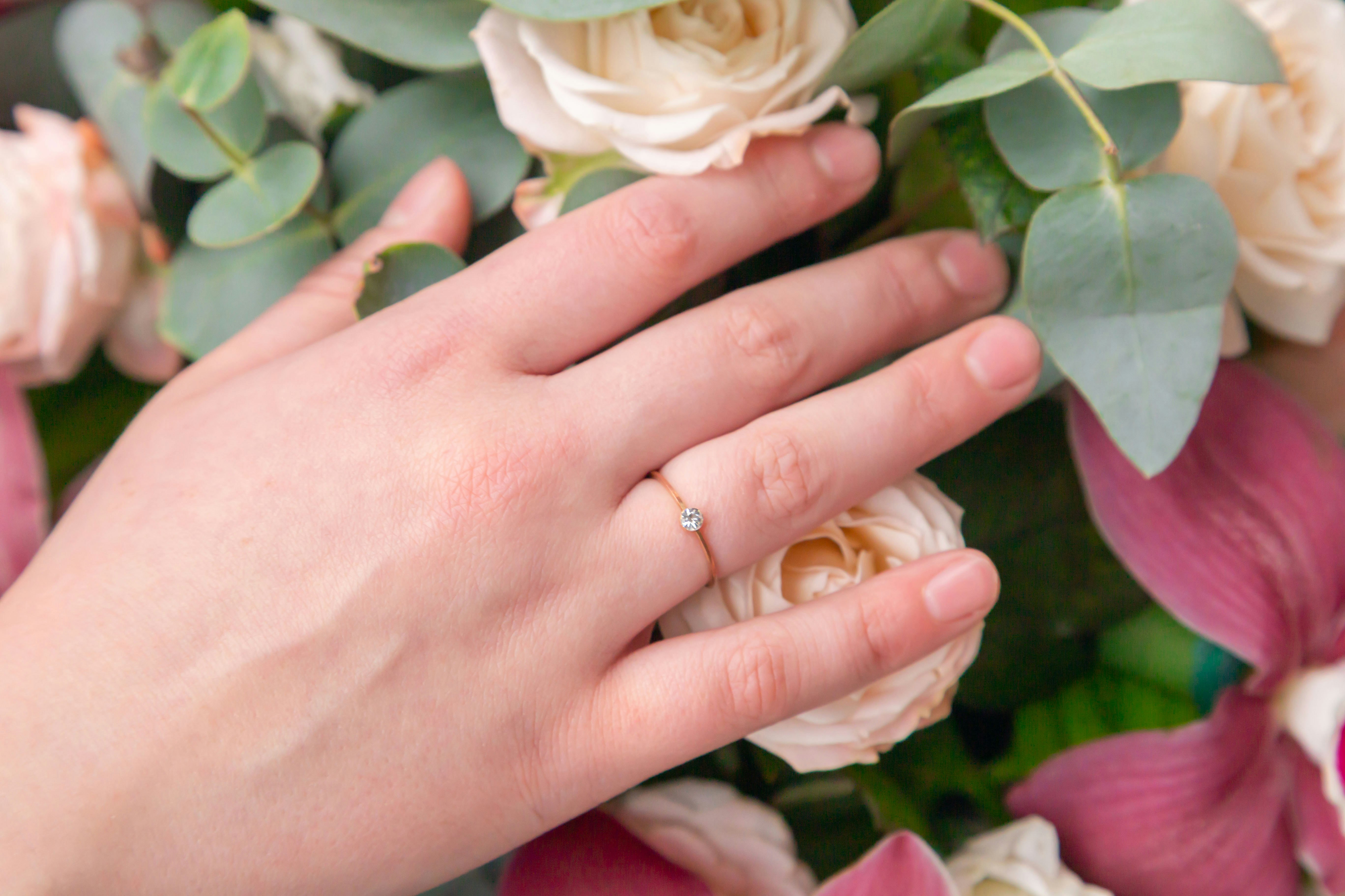Close-up of a girl's hand wearing a wedding ring lies on a bouquet of beautiful flowers. Bride. An offer of marriage. Wedding. Bouquet. Top view. Close-up.