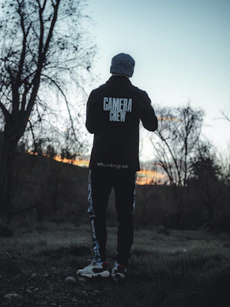 Technician in uniform inspecting a home's exterior for pests at dusk.
