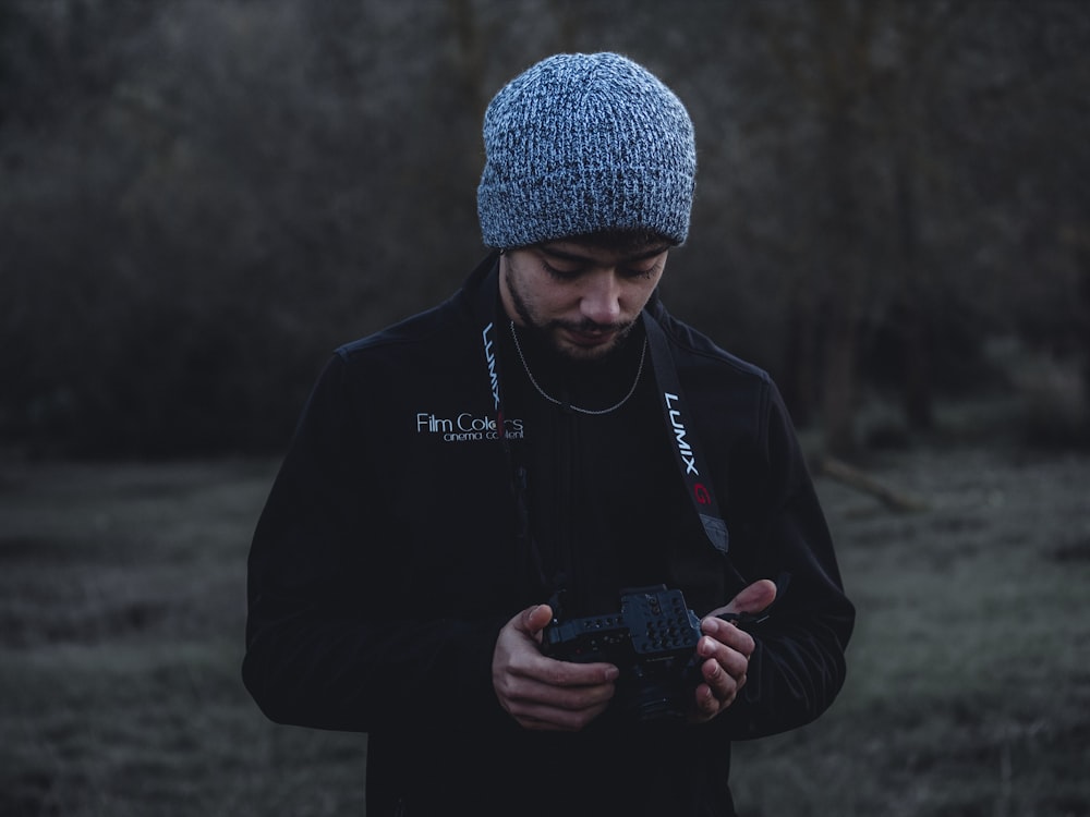 man in black jacket holding black smartphone