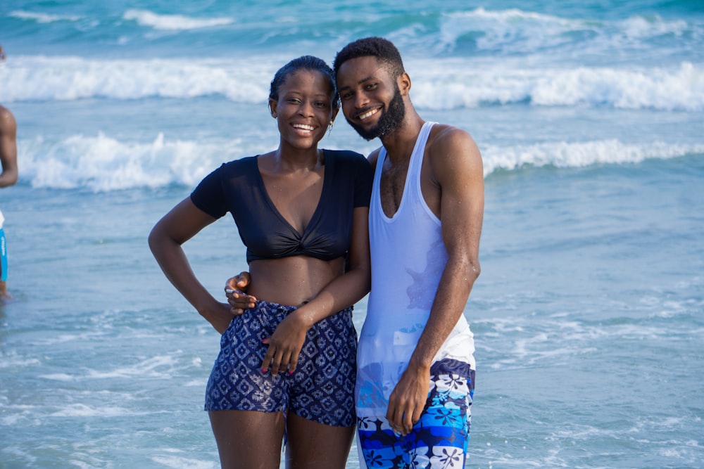 woman in black tank top and blue and white floral skirt standing on beach during daytime