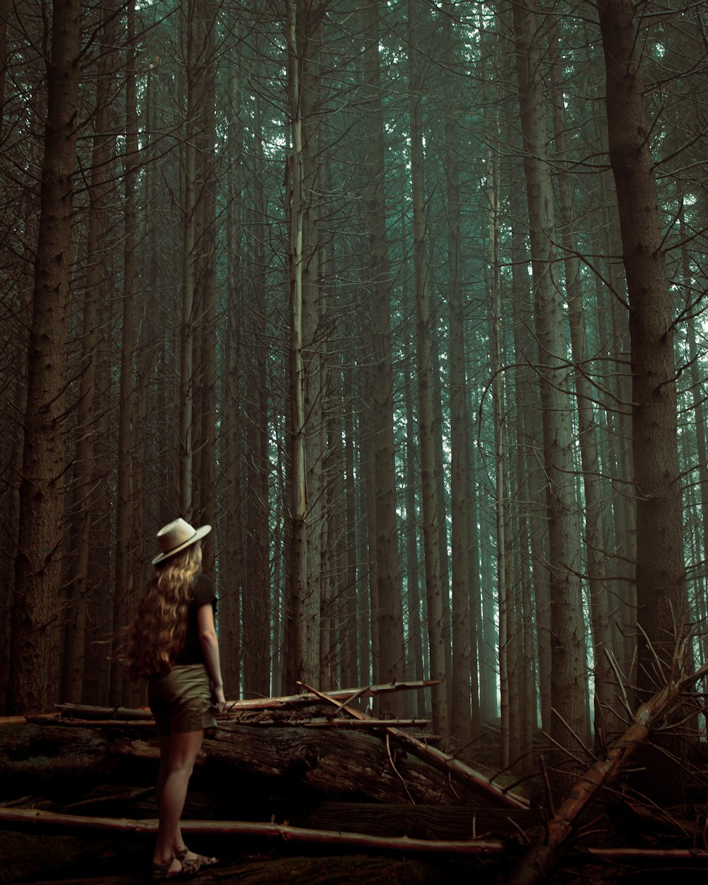 woman in brown hat standing on brown tree trunk during daytime