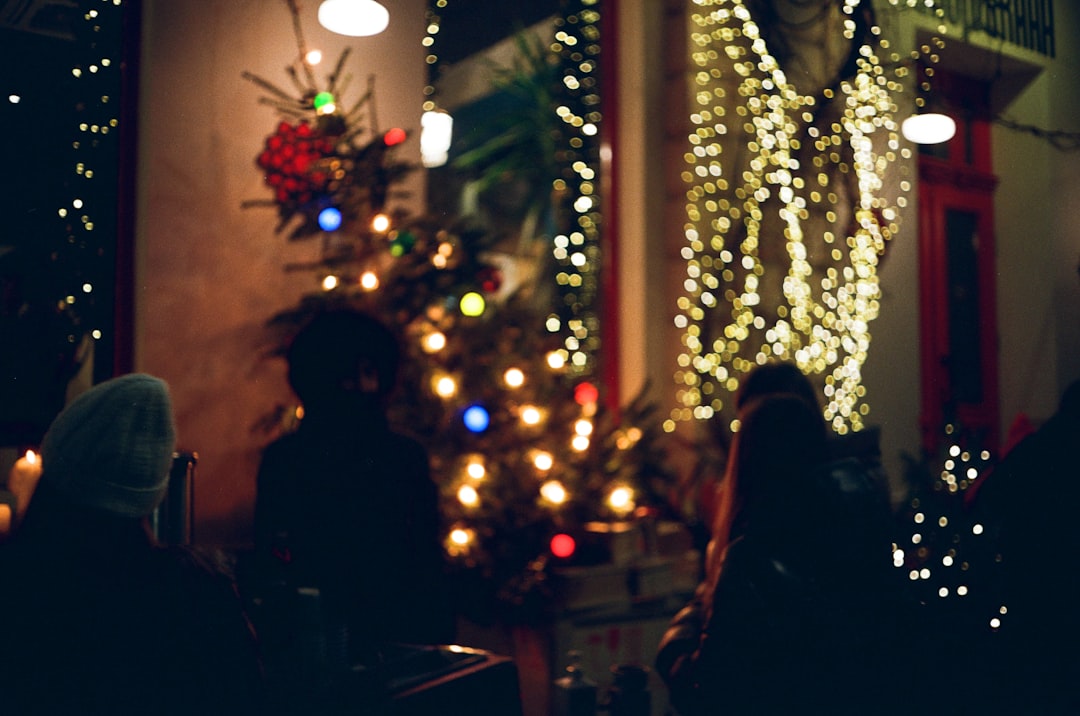 woman in black long sleeve shirt standing beside lighted christmas tree