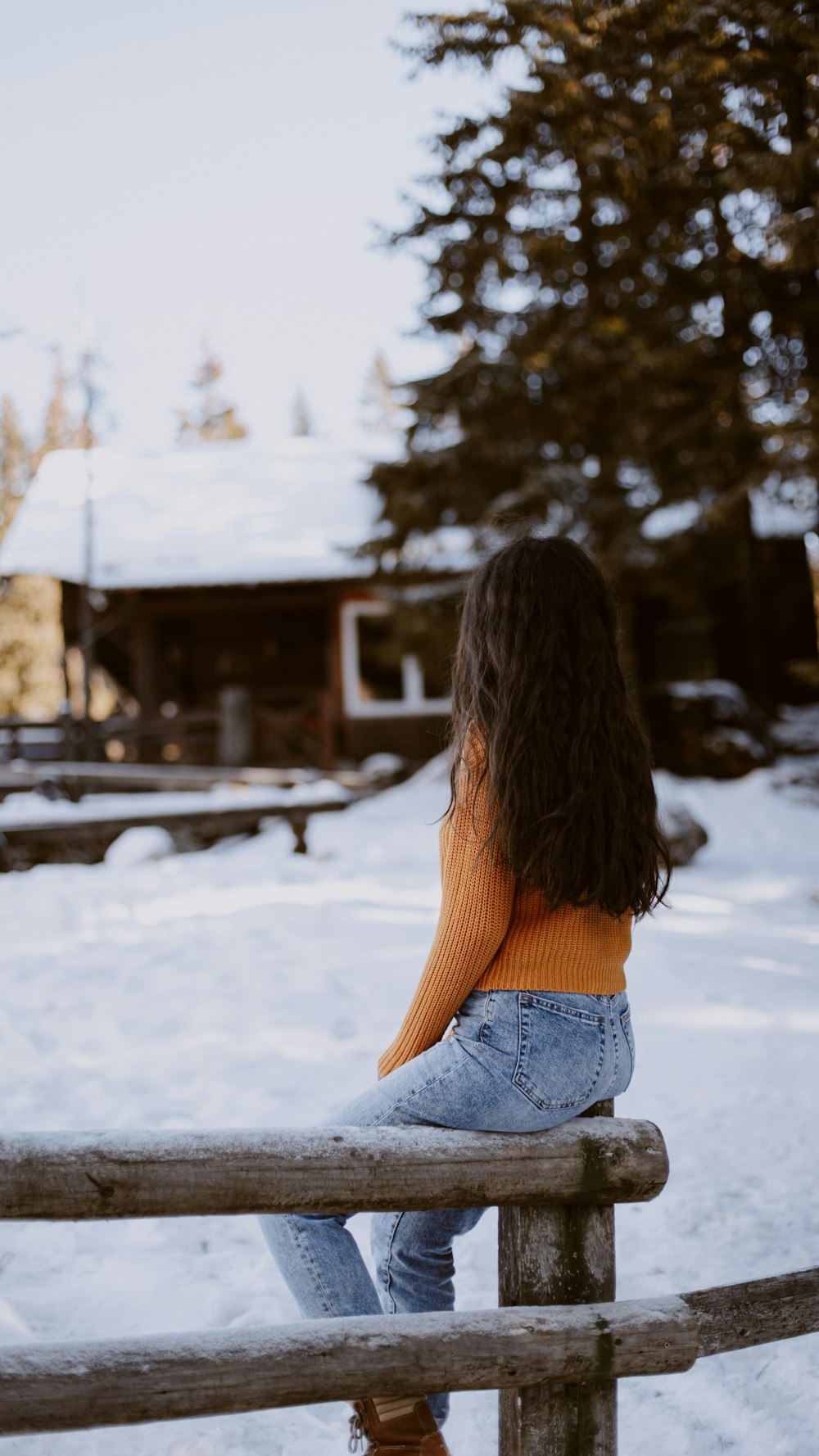 Mujer en jeans de mezclilla azul sentada en suelo cubierto de nieve durante el día