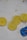 Several lemon slices arranged in a row on a light background with some brown stains nearby. A small blue toy car is positioned close to the lemon slices.