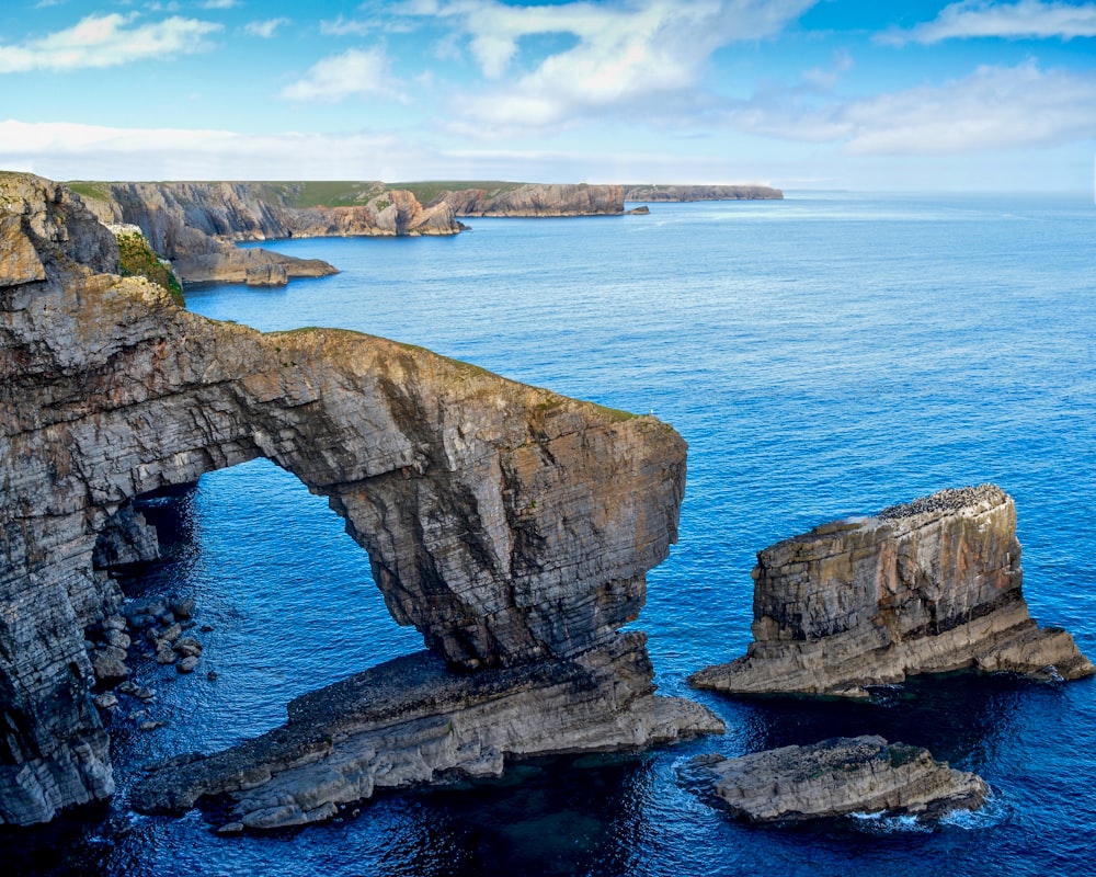 brown and green rock formation on blue sea under blue sky during daytime