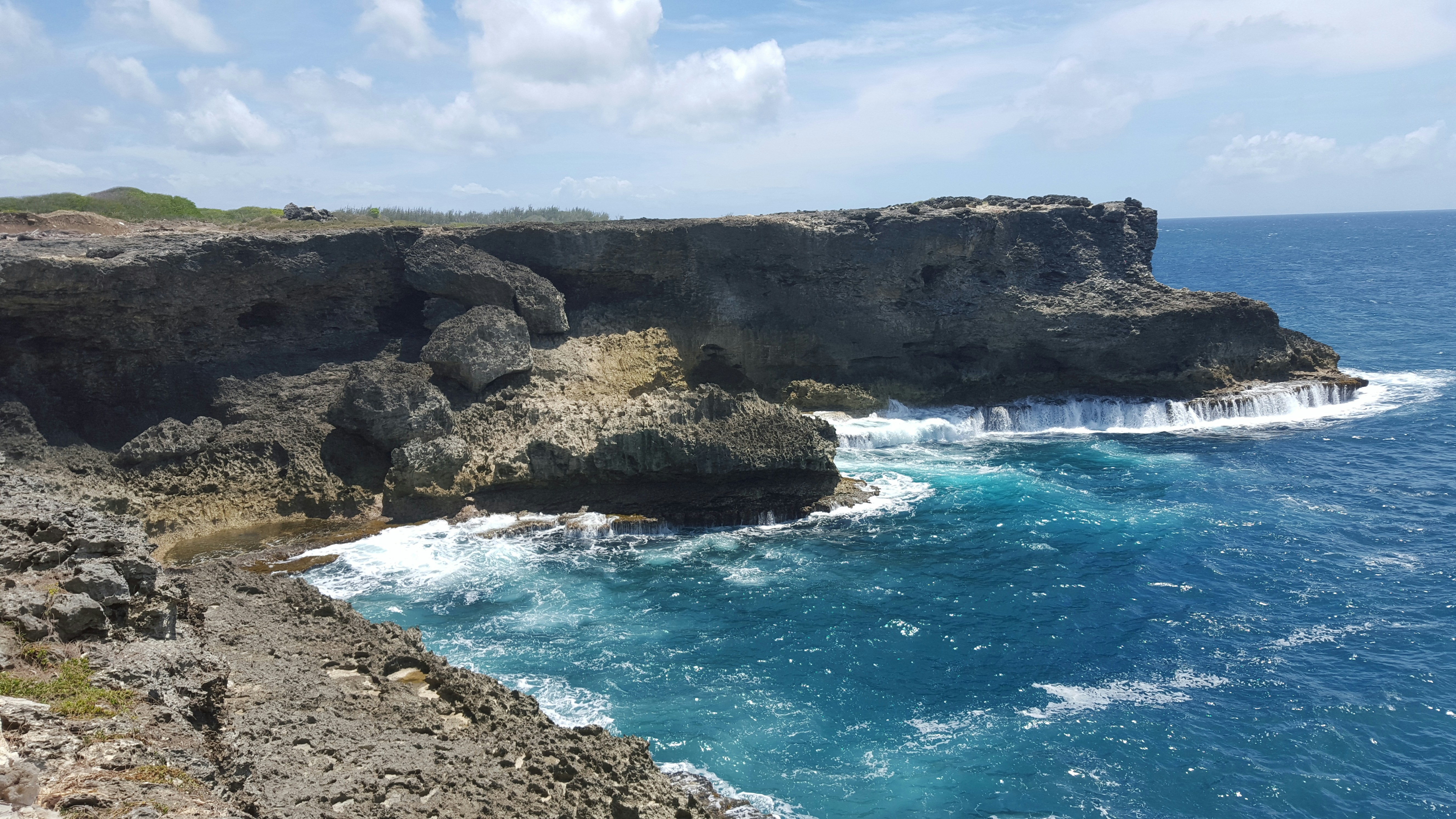 brown rocky mountain beside blue sea under blue sky and white clouds during daytime, Animal Flower Cave, St. Lucy, Barbados