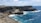 brown rocky mountain beside blue sea under blue sky and white clouds during daytime